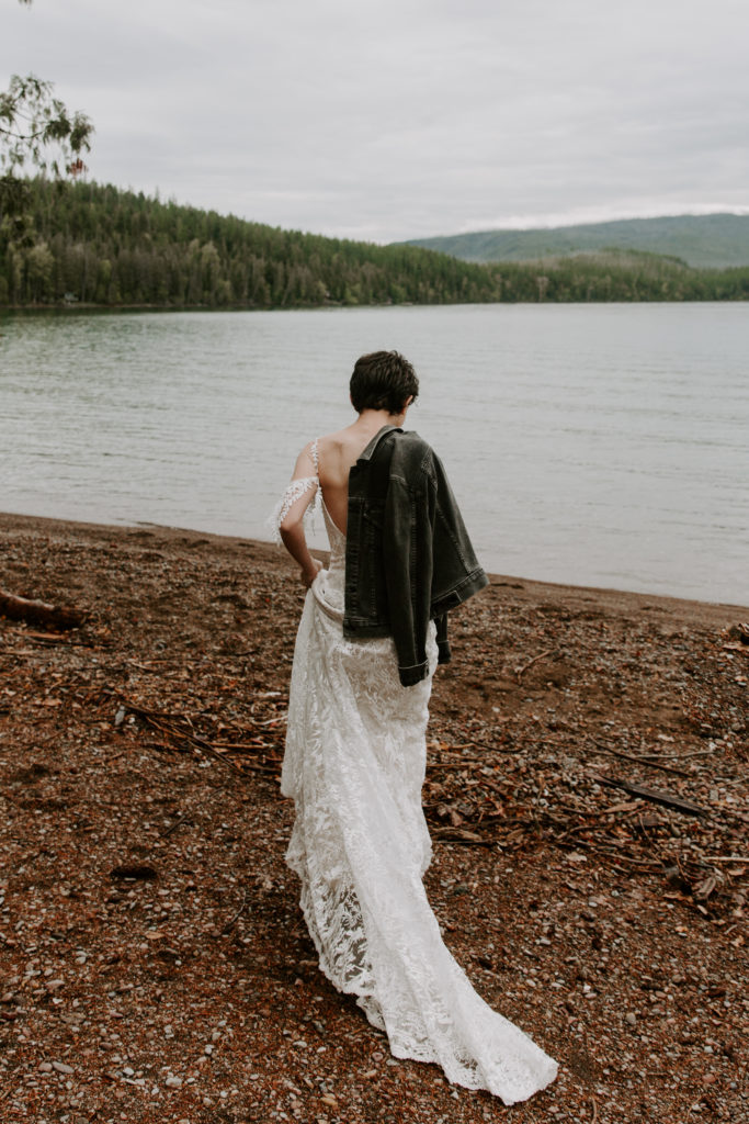 Woman holding a jacket over her shoulder as she walks towards the lake during her Montana elopement