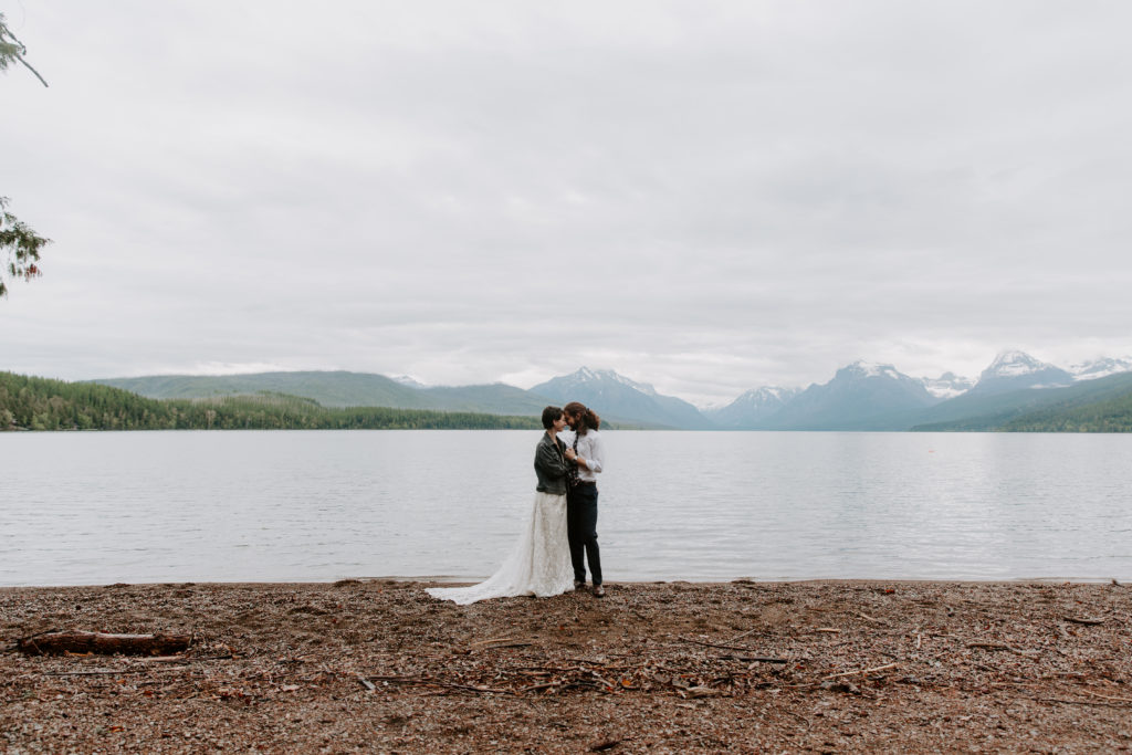 Couple standing on the edge of Jenny Lake leaning their foreheads together during their early morning Montana elopement