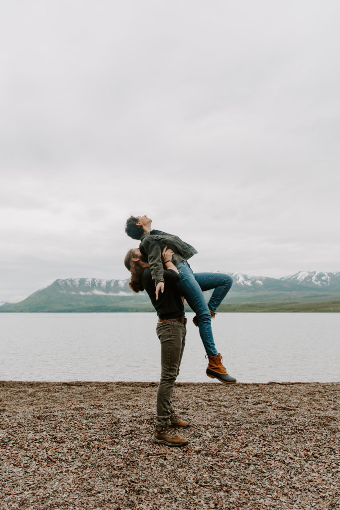 A man lifting his partner up in the air as she kicks her feet out and holds her arms and head back during their Montana elopement