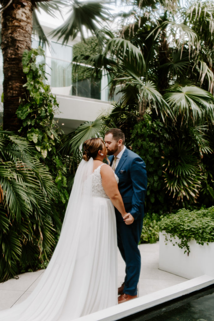 A couple sharing a kiss on a pathway at their hotel during their first look