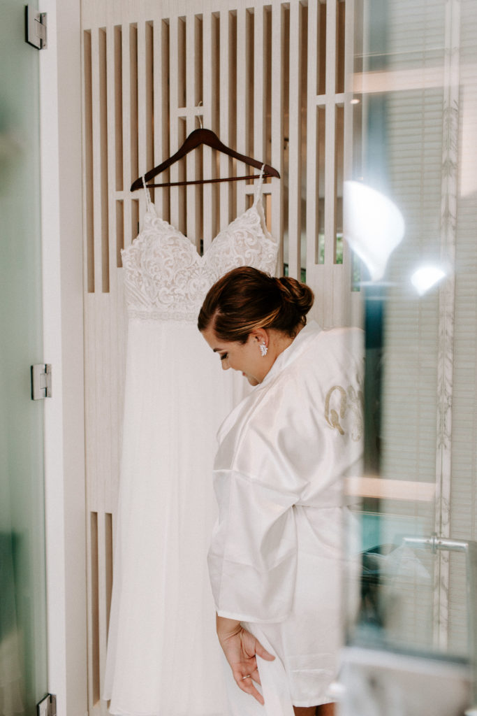 A bride admiring her wedding dress as it hangs up during getting ready for her key west wedding