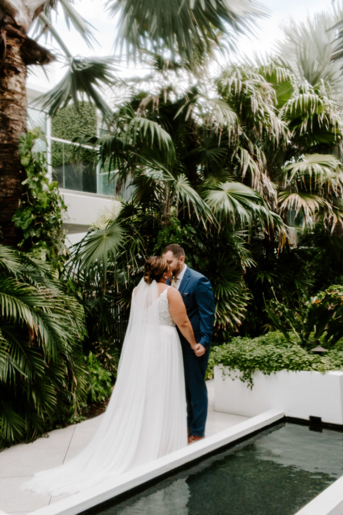 A couple sharing a kiss during their first look surrounded by palm trees in key west
