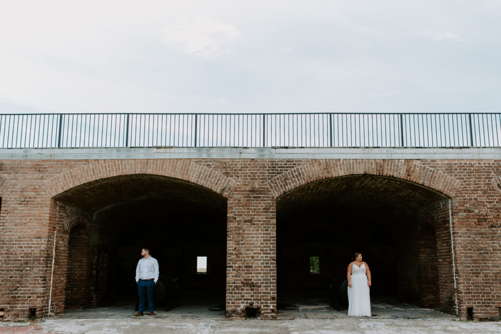 A man and a woman standing in two separate arches at Fort Zachery Taylor and looking the opposite direction during their Florida keys elopement
