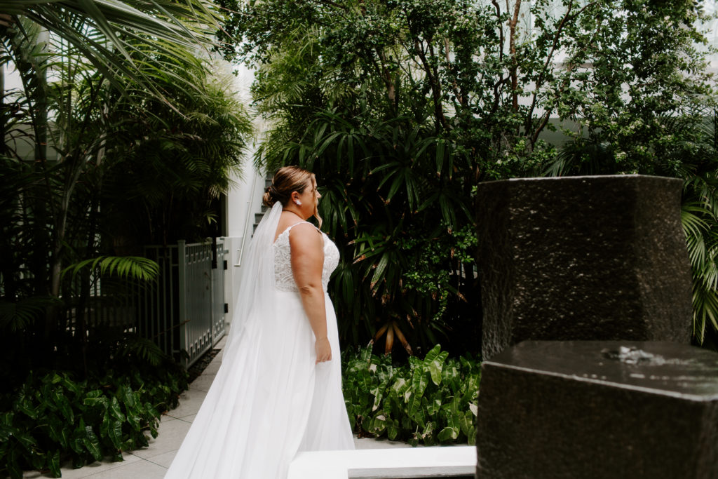 A woman walking along the path of their hotel in her wedding dress to show her partner during their key west elopement