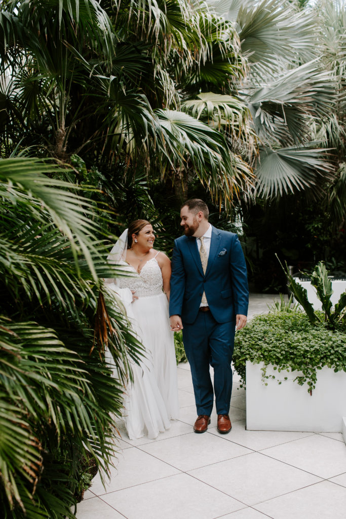A couple holding hands and walking down the path of their hotel after their first look during their key west elopement