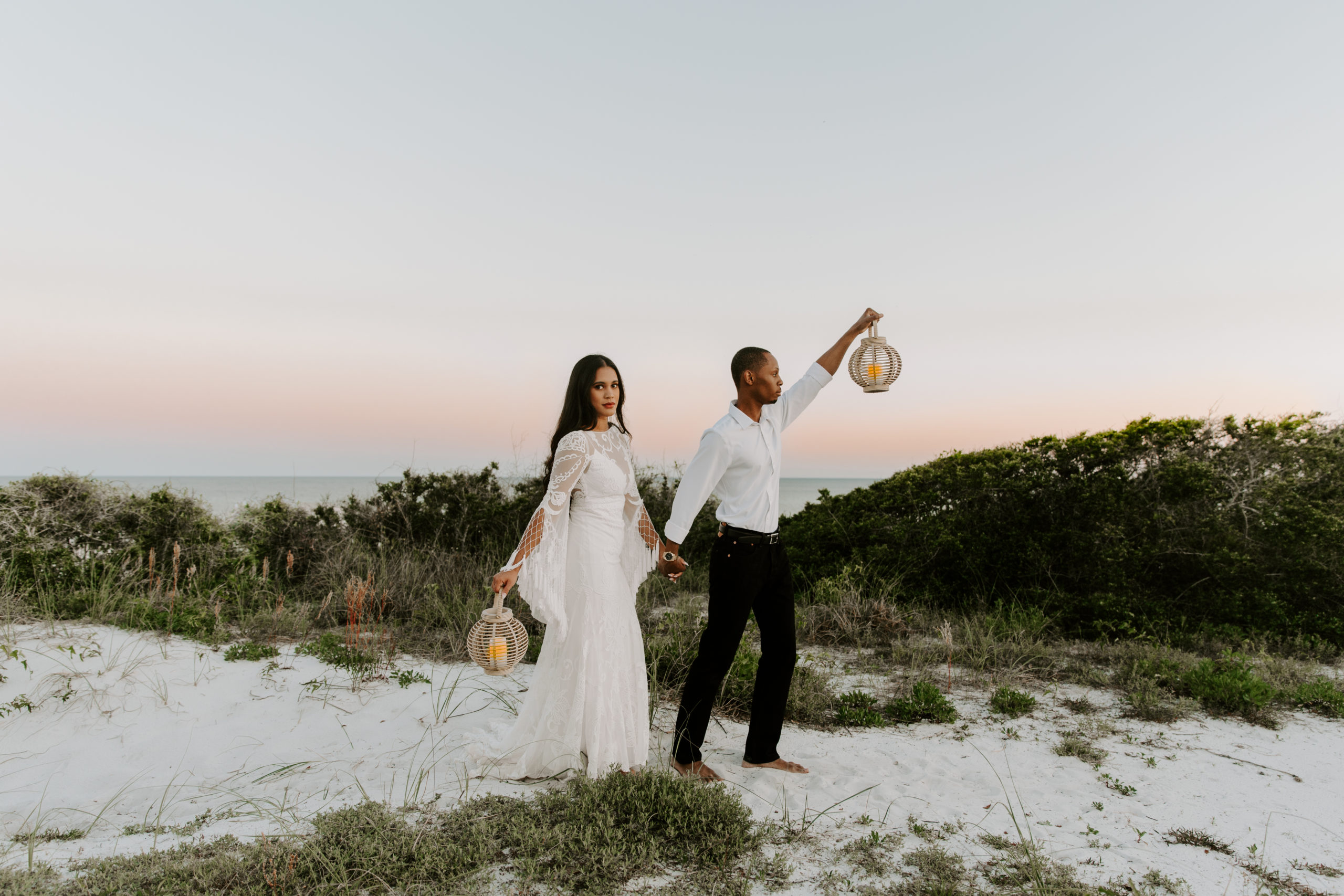 Newly wed couple holding lanterns as they are exploring the local seashore during their Florida elopement