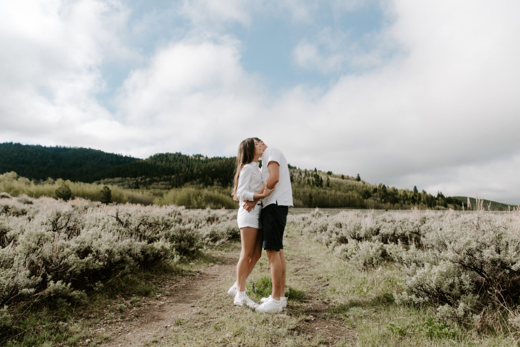 A couple hugging while standing in a field during their Jackson Hole, Wyoming engagement photos