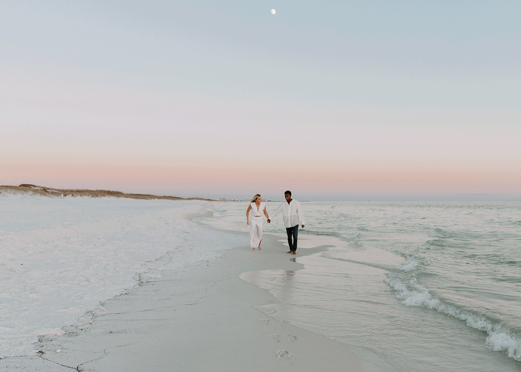 Couple holding hands and running along the beach during their beach engagement photos in Florida