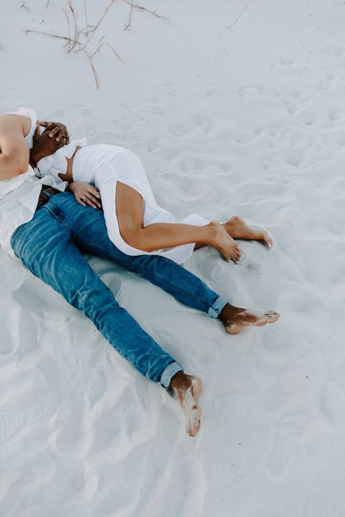Couples legs intertwined as the couple is laying on the beach during their Fort Walton beach engagement photos