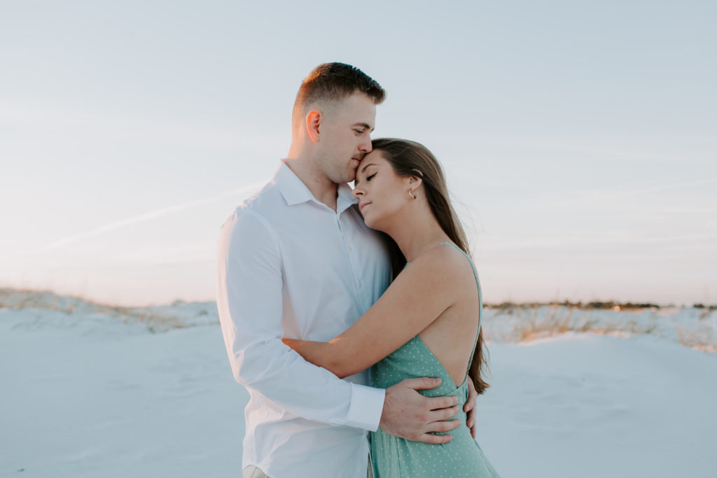 Man leaning into his partners head as she is holding onto him during their Destin engagement photos