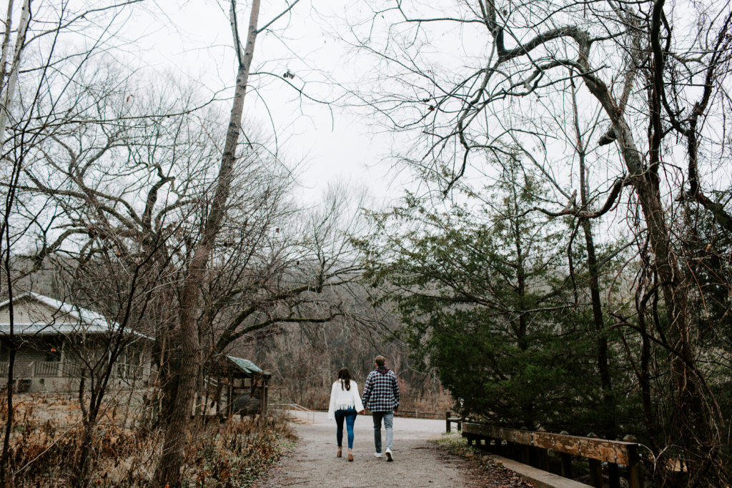 Couple holding hands and walking with their backs to us down a path during their Tennessee engagement photos