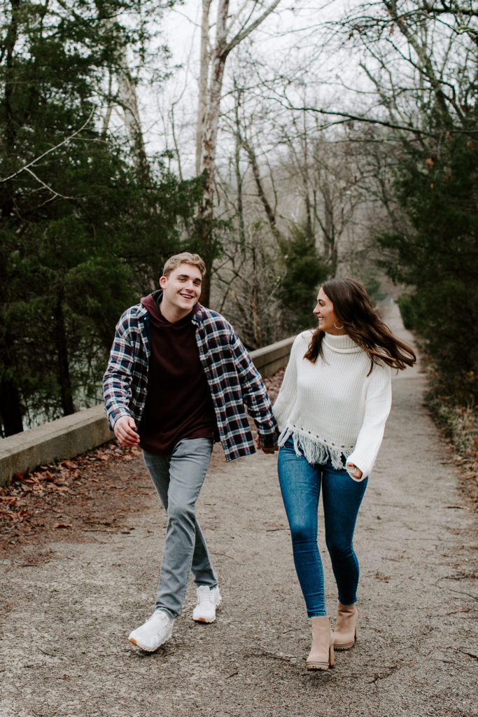 Man laughing as he is holding his partners hand and walking down a path during their Tennessee proposal