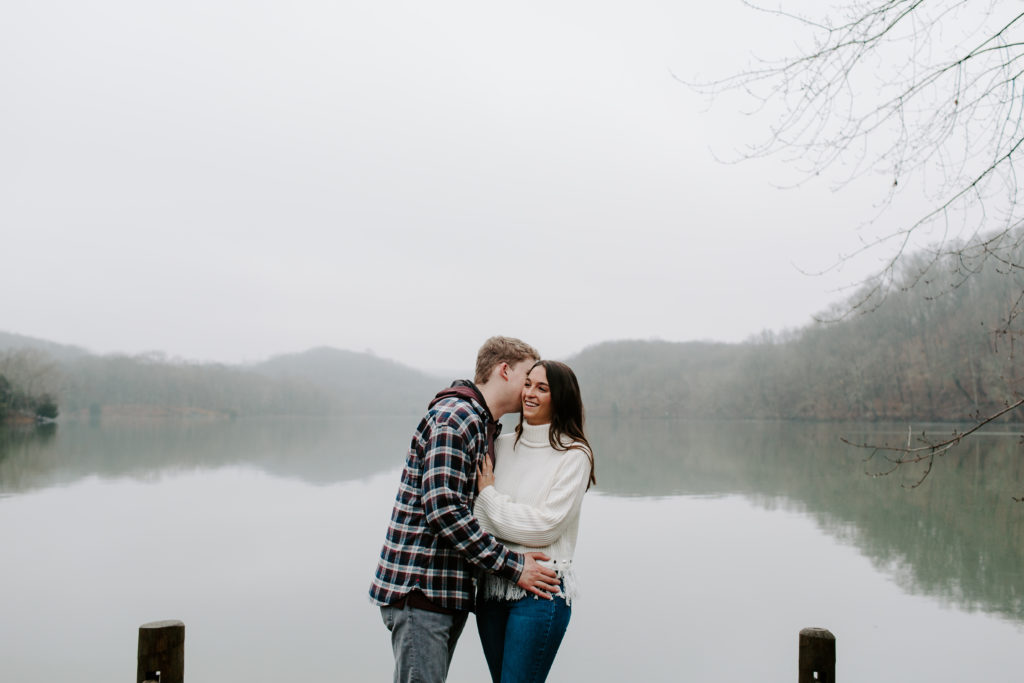 A man whispering into his partners ear as she is laughing and holding onto him during their Tennessee couple photos