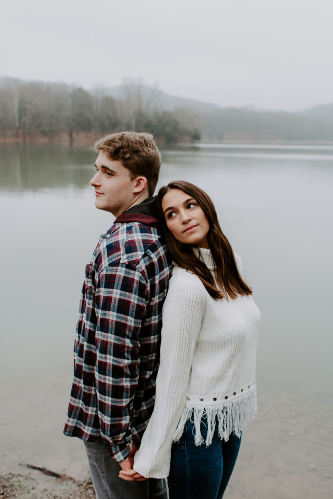 Woman leaning against her partner as they hold hands and look off into the distance during their engagement photos in Tennessee