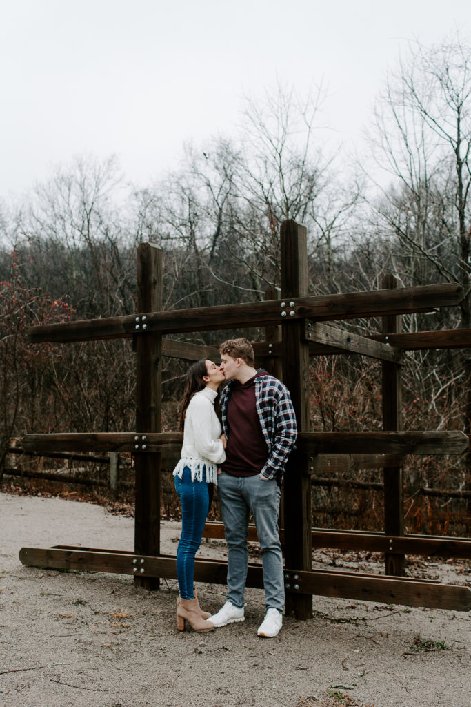 Couple sharing a kiss as the man leans up against a boat rack during their Tennessee engagement photos