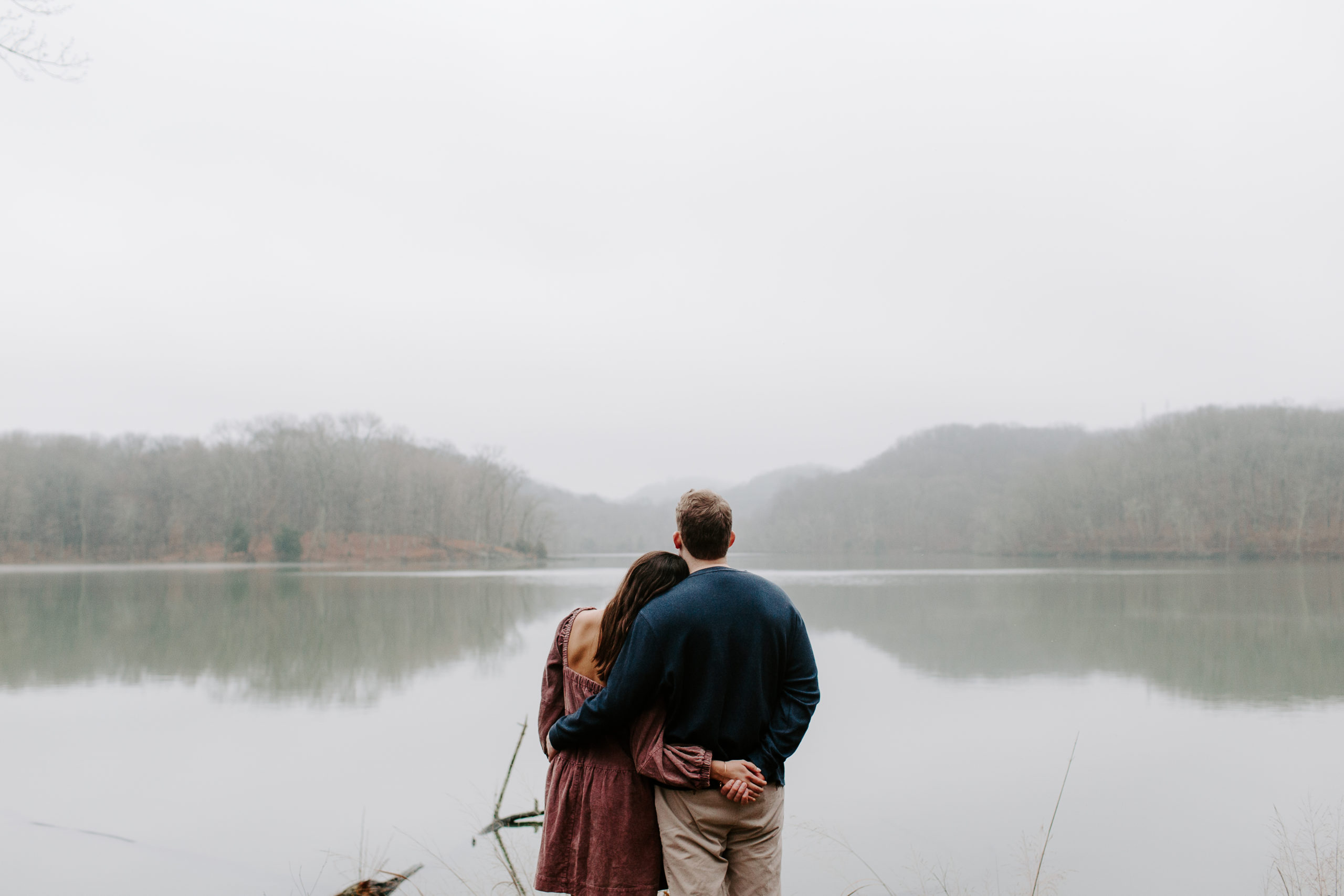 Woman leaning her head against her partner as they are holding hands behind their bodies during their winter engagement photos in Tennessee