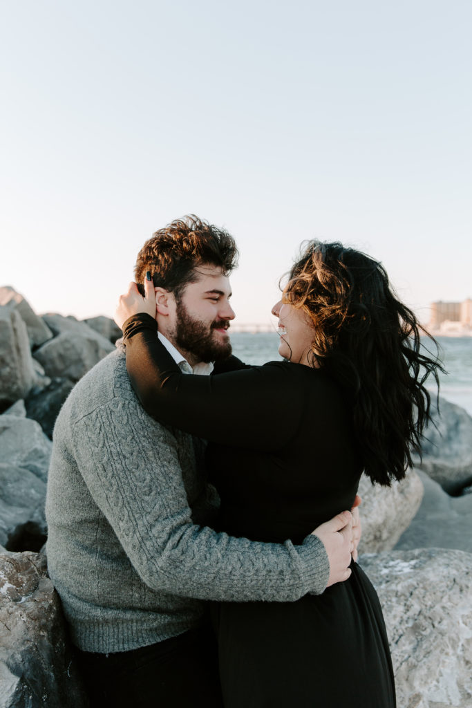Woman running her hands through her partners hair as he is smiling at her during their couple photos