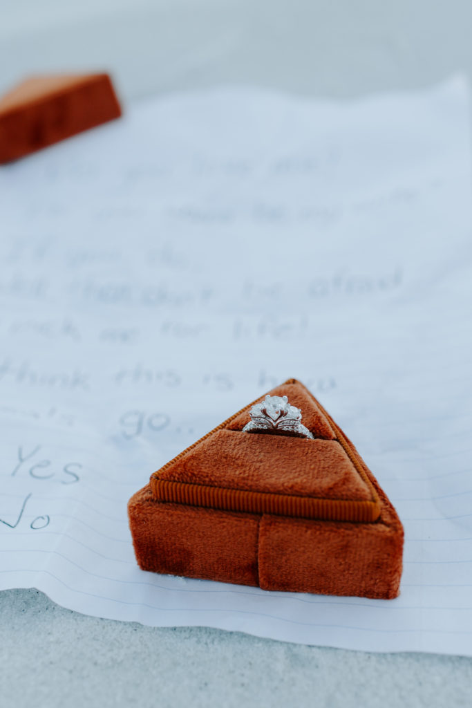 An engagement ring sitting in an orange triangle ring box