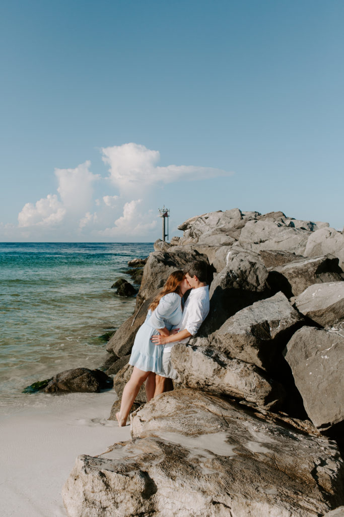 Couple leaning up against the jetties in Destin after getting engaged in Florida