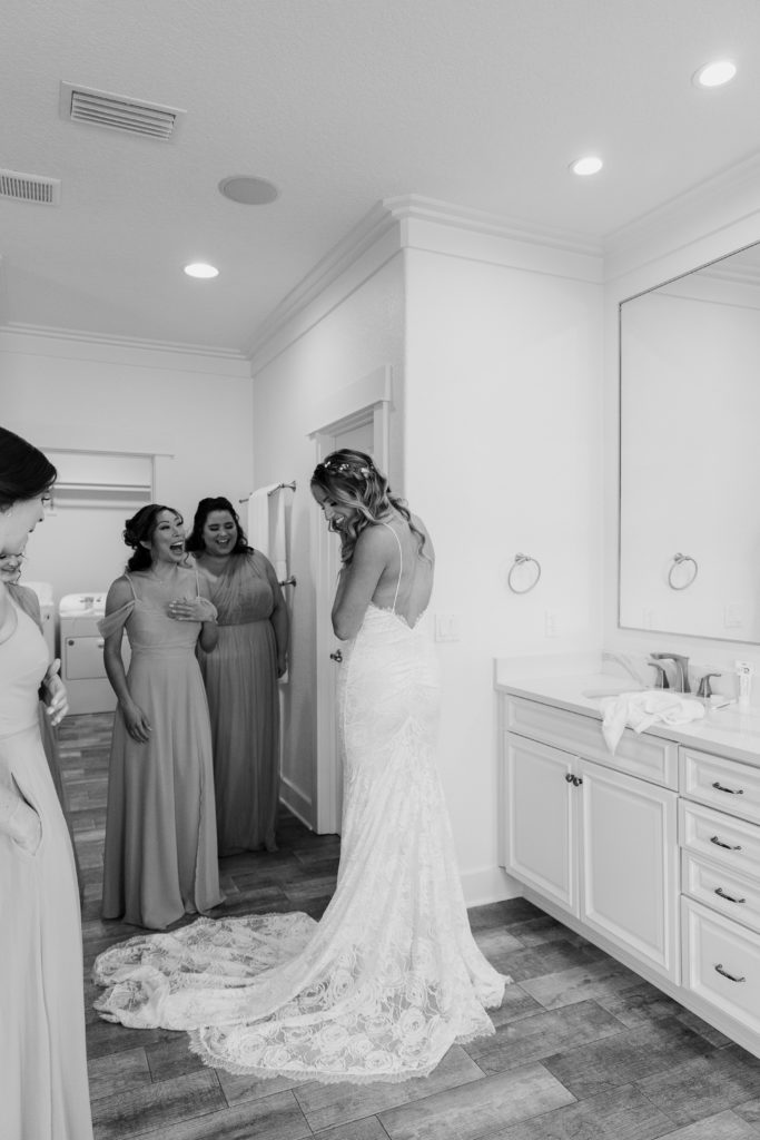 Woman in her wedding dress showing all her bridesmaids it for the first time as they are all getting ready during her Florida wedding