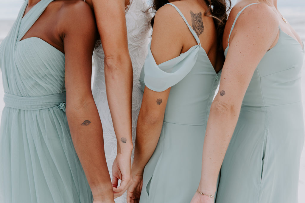 Bride and bridesmaids showing off their matching tattoos during a Miramar Beach wedding