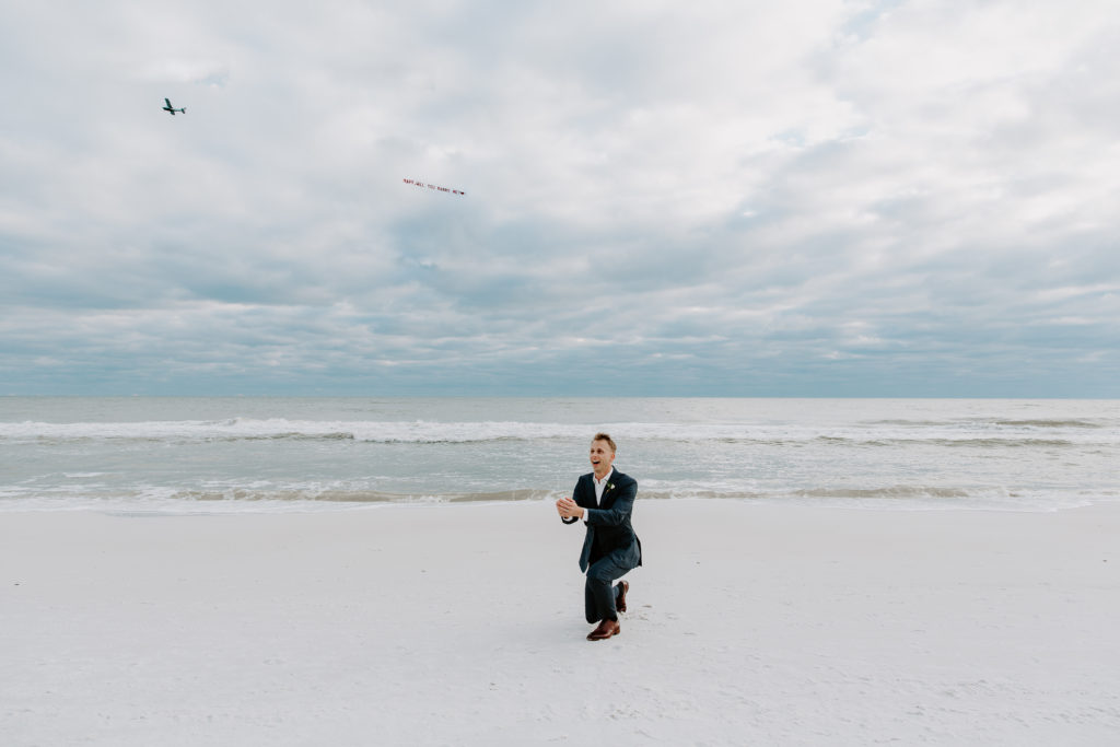 Man fake proposing during his wedding as a plane flies over asking a woman to marry him during his beach wedding