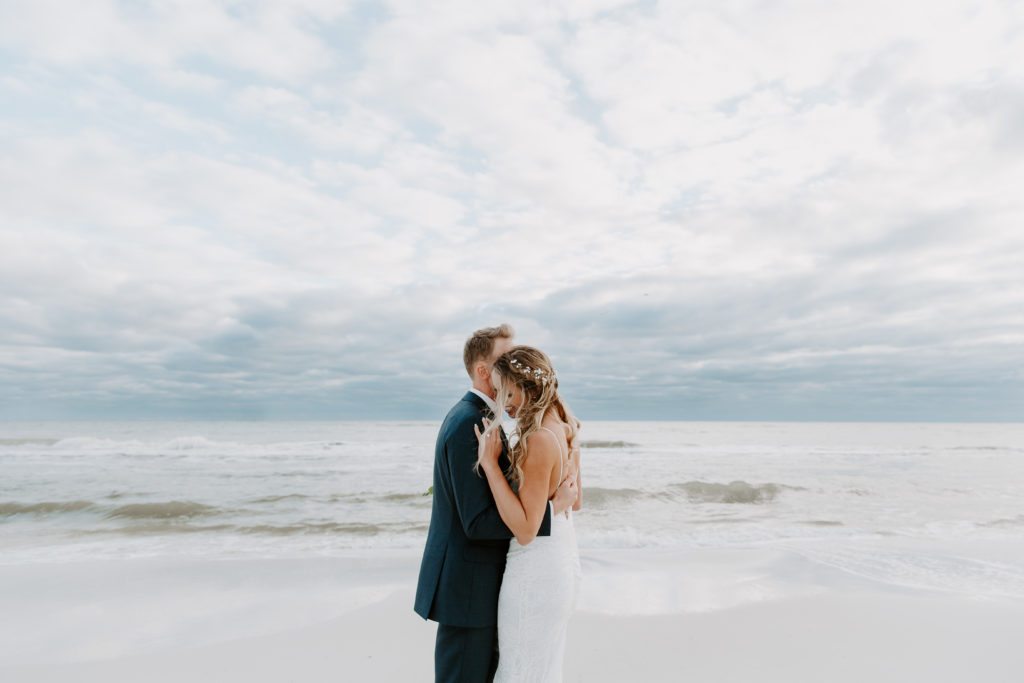 Couple hugging onto each other as the wind moves the woman's hair during their Florida beach wedding in Destin