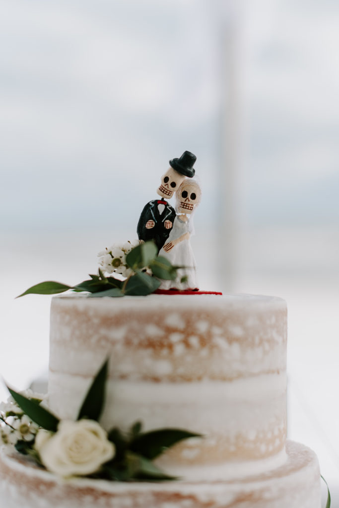 The gothic skull bride and groom cake topper during a Halloween beach wedding