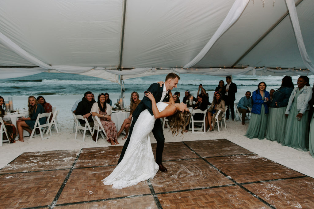 Man dipping his partner during their first dance after their beach vow renewal in Destin
