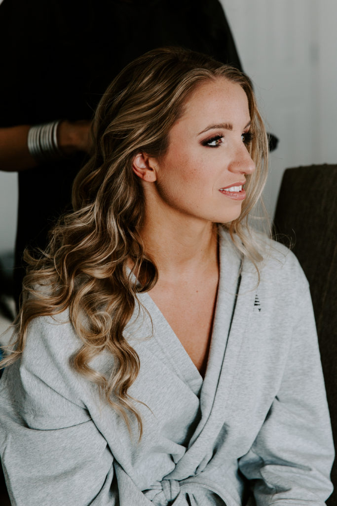 Woman looking off into the distance as she gets her hair and makeup done on her wedding day in Florida
