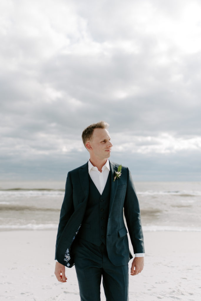 Groom walking away from the ocean during his 30A beach wedding