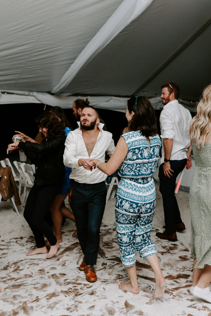 Man with his shirt half unbuttoned dancing with a partner during a wedding reception in Miramar Beach
