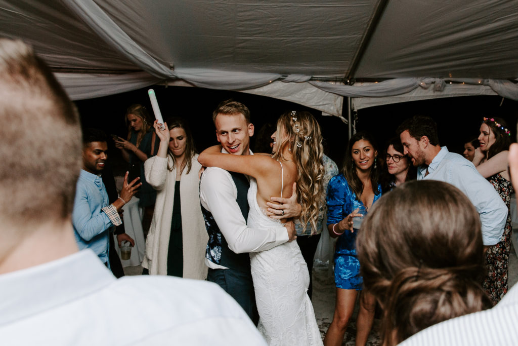Groom holding onto his bride and dancing with her on the dance floor during their Miramar Beach wedding