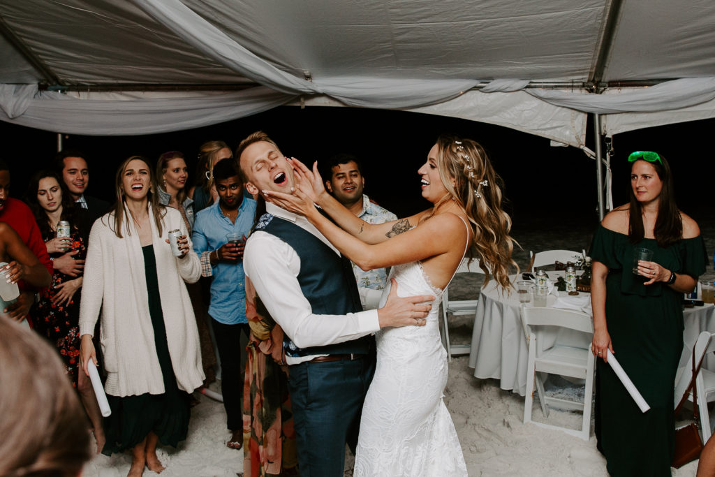 Woman holding on to her partners face as he is singing during their Destin wedding