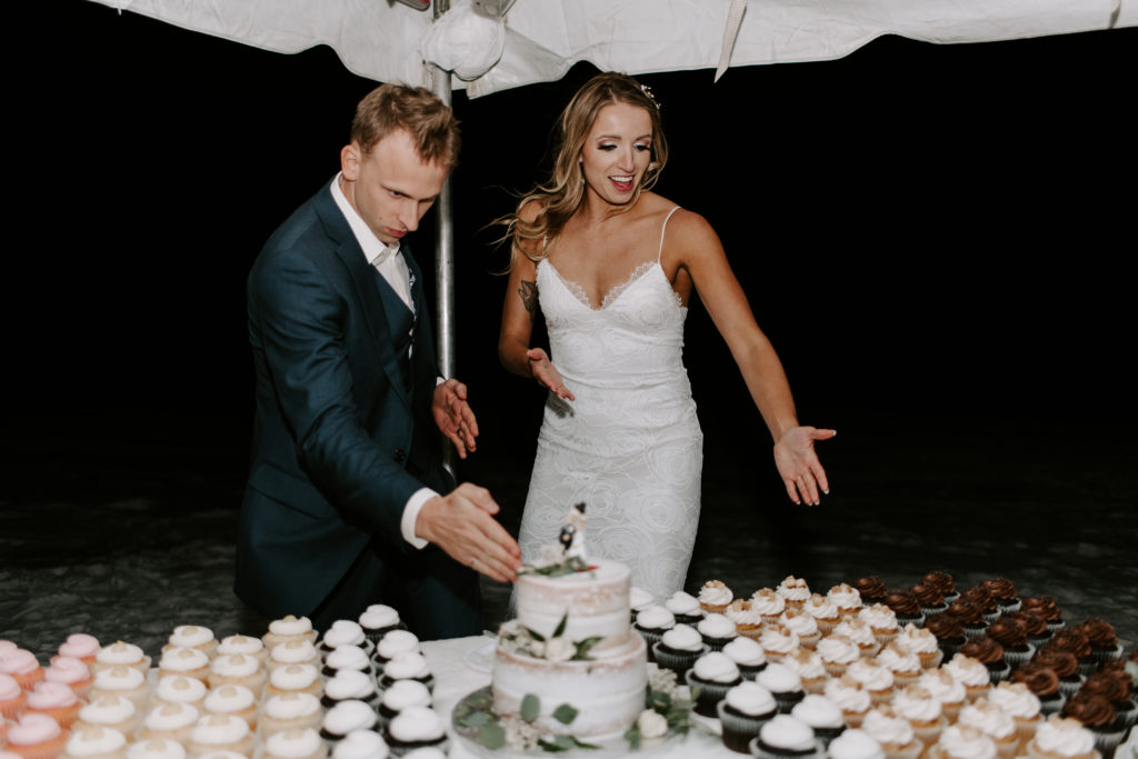 Couple pointing to the dessert table as they are about to cut the cake during their beach vow renewal