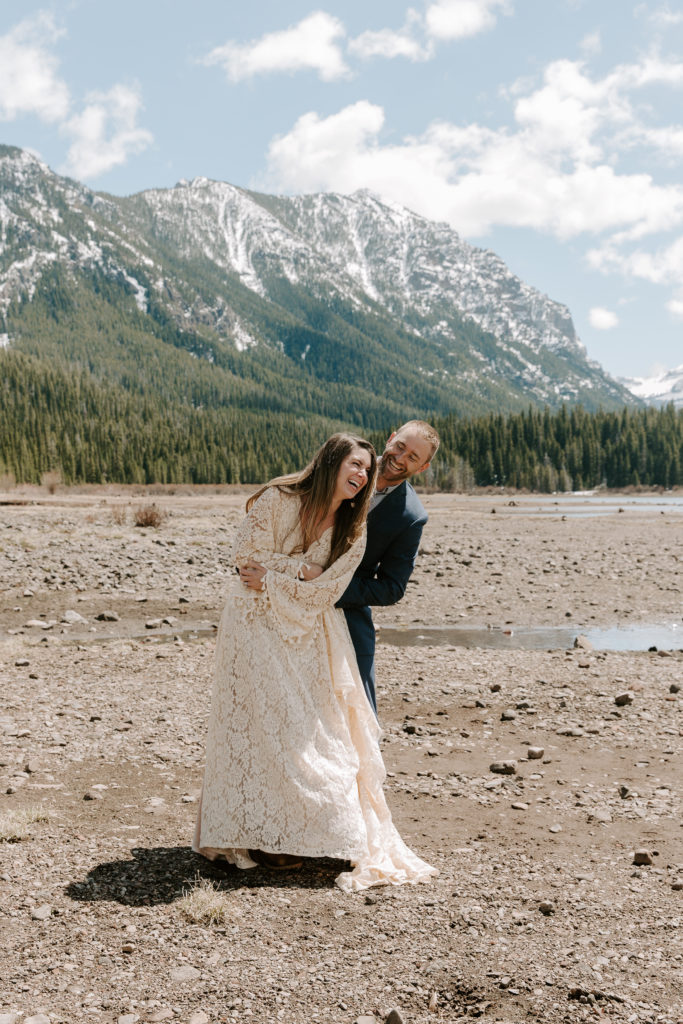 Man wrapping his partner with his arms behind as she is laughing during their summer Montana elopement