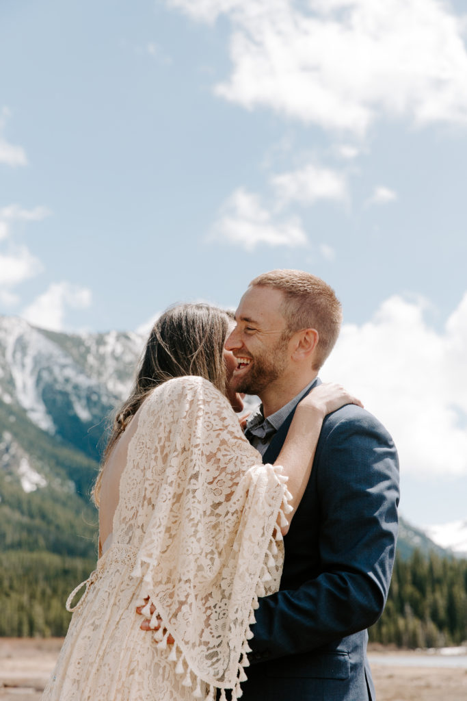 Woman whispering into her partners ear as he is laughing during their Montana elopement