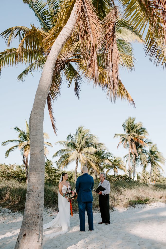 Couple sharing their vows surrounded by large palm trees during their key west elopement