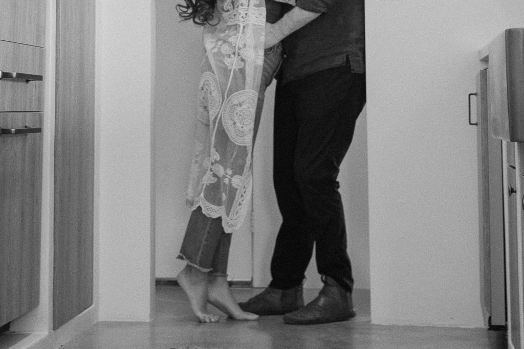 A couple standing in in a doorway facing each other as the woman is on her tip toes during their in home couple session in Southern California