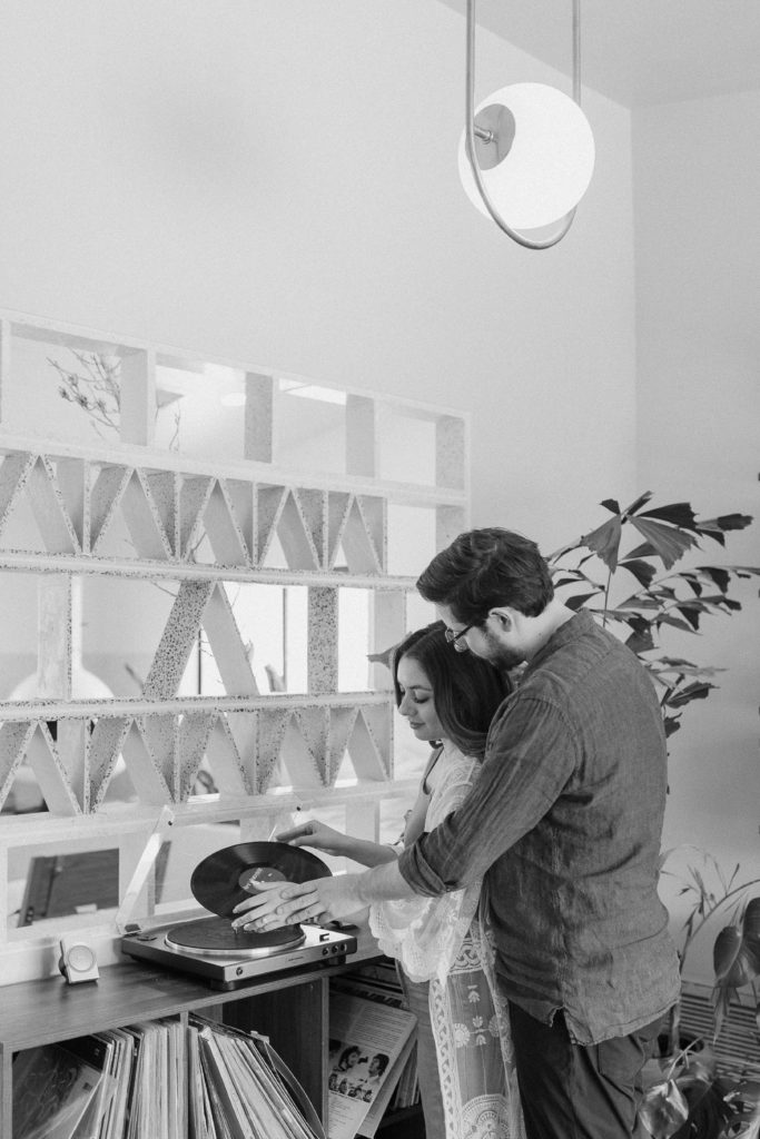 A newly engaged couple placing a record on their record player during their California engagement session