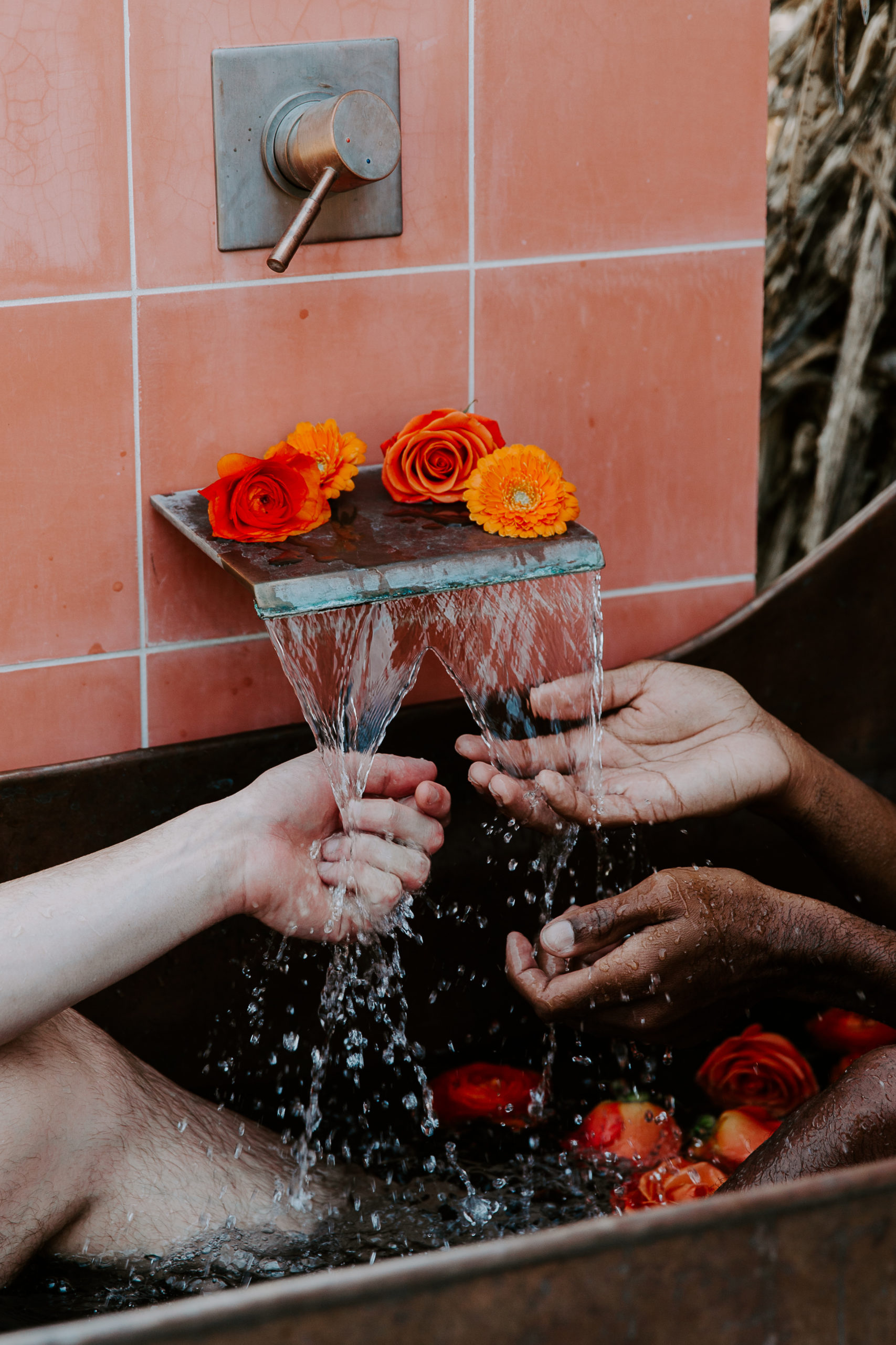 A couples hands under a water spout as the water is coming out and running over their hands during their intimate couple session at AirBNB in California