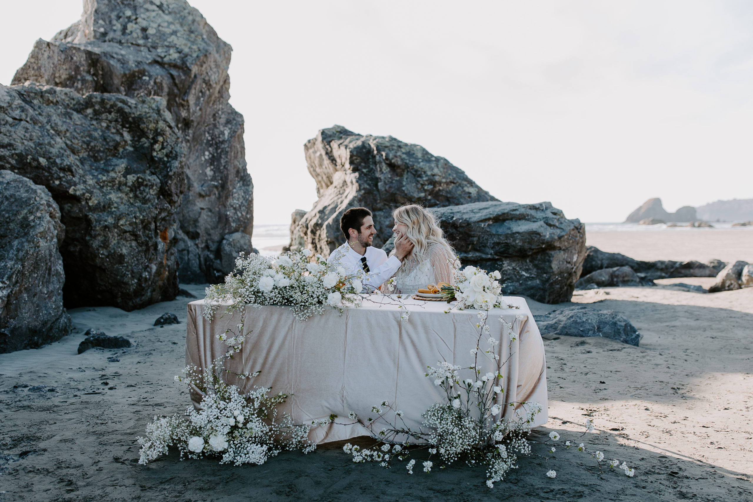 A newly wed couple sitting at their wedding table during their coastal micro wedding in Northern California