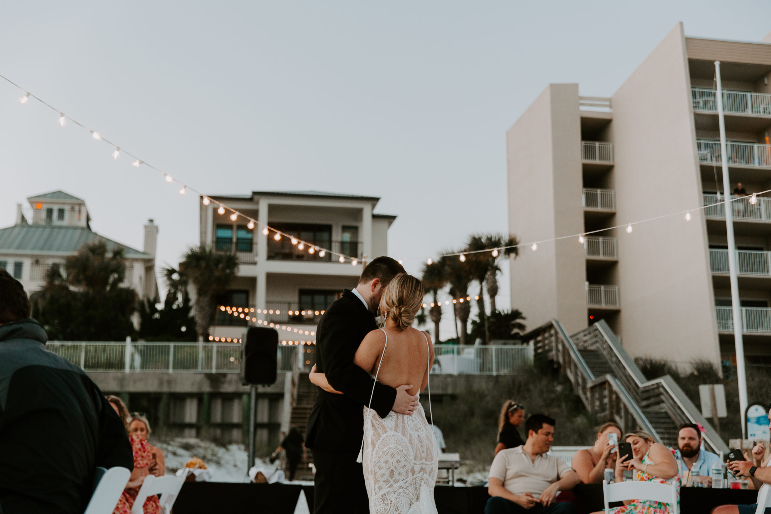 A newly wed couple sharing their first dance under twinkle lights during their beach wedding reception in Florida