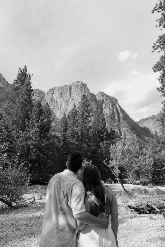 Couple with their arms around each others waist looking off into the distance at El Capitan in Yosemite