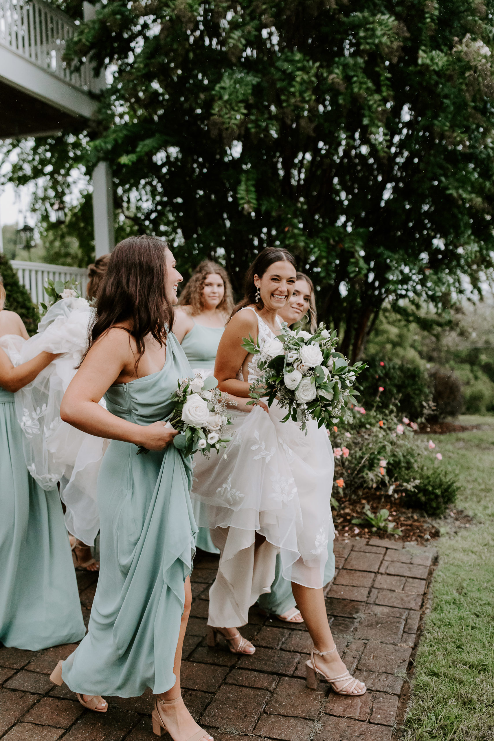 Bride walking down stairs surrounded by her bridesmaids that are helping her hold her dress during her Tennessee wedding