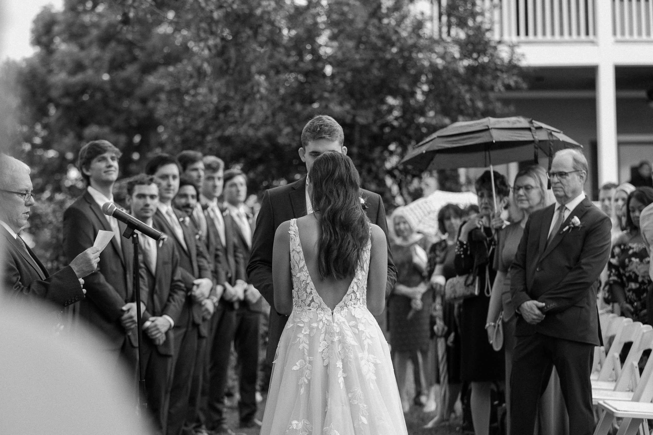 Couple standing up at the alter holding hands with their wedding party on one side and guests on the other during their Front Porch Farms wedding