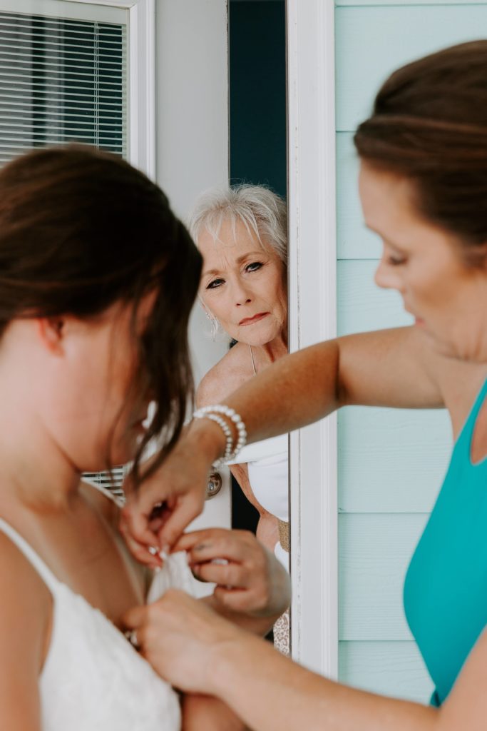 A grandma sticking her head out the door as she watches her daughter help her daughter get ready for her wedding on Pensacola Beach