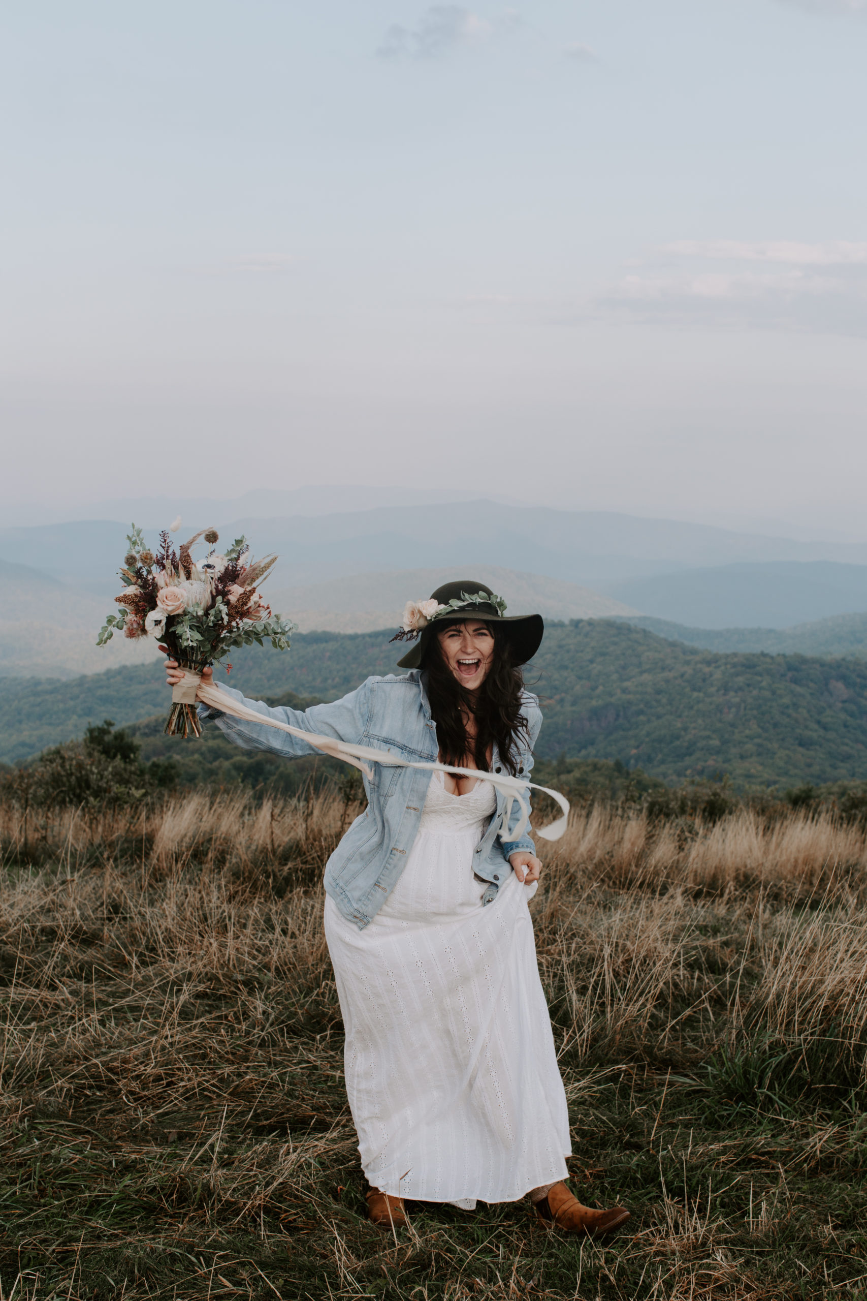 Woman throwing up her wedding bouquet with a big smile on her face during her sunrise mountain elopement in North Carolina