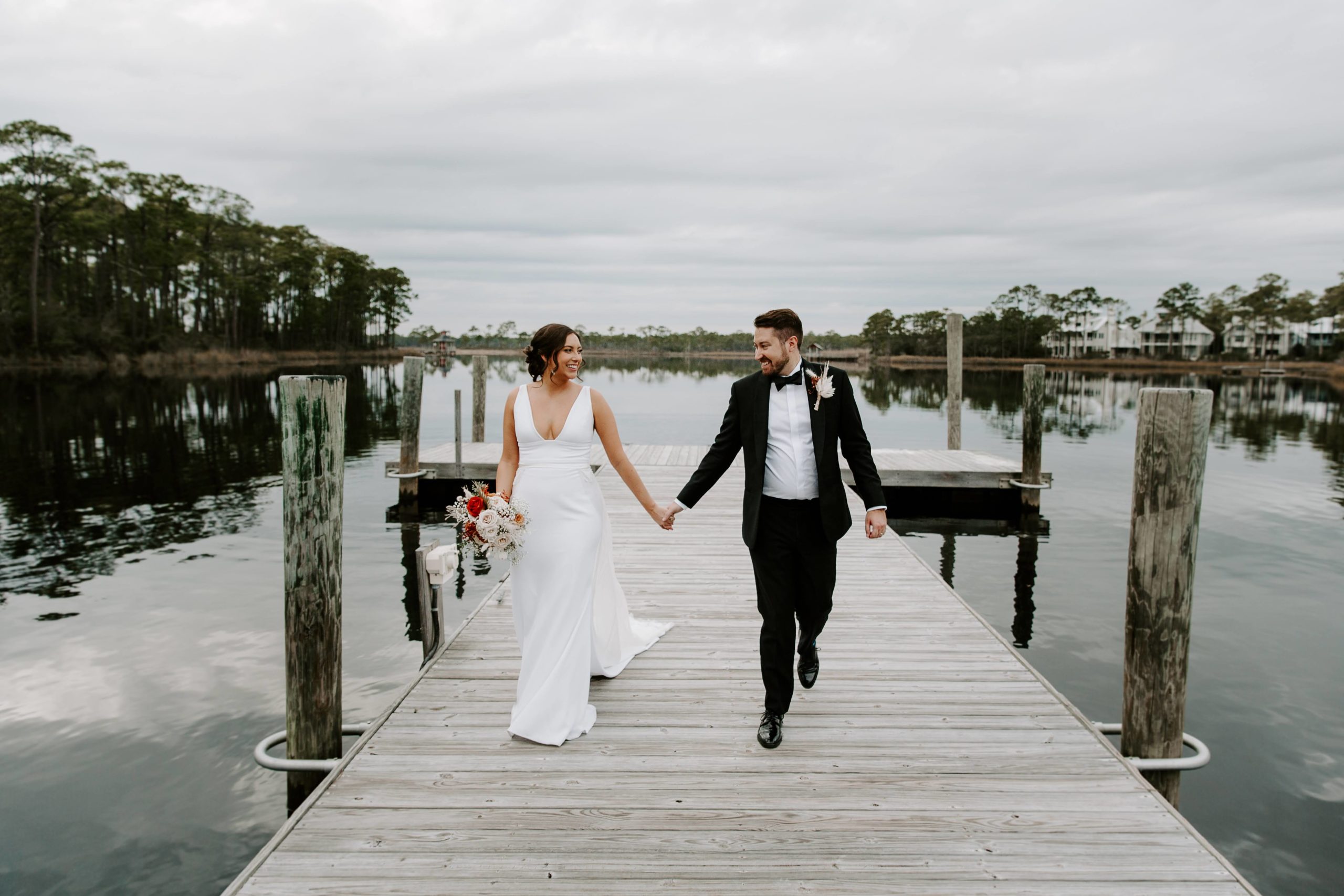 Couple holding hands and walking along a dock during their 30a cocktail hour