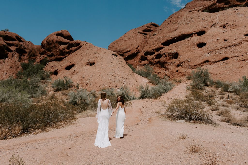 A woman leading her partner up the side of a mountain in the desert during their Arizona elopement 